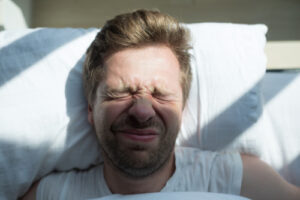 Sleeping man disturbed by sun