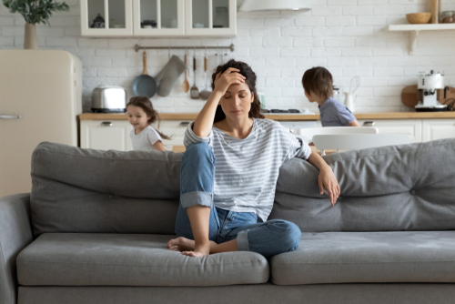 woman sitting on couch and holding her head