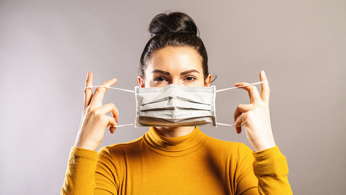 woman putting mask on her face