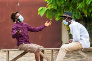 two men sitting on bench wearing masks