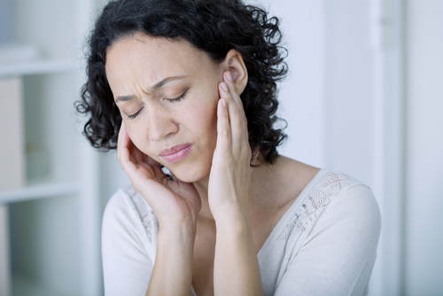 A woman in distress holding her ears