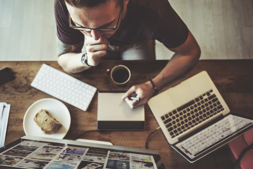 man sitting at table with laptop and coffee