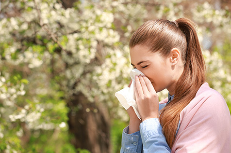 woman with allergies using tissue